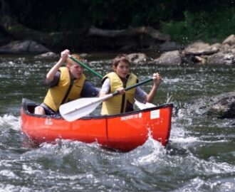 two young boys navigating the waves of the water in their canoe Downriver Canoe Company Shenandoah Valley River